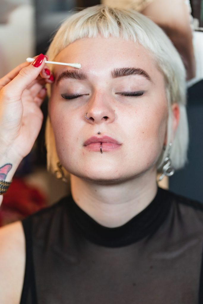 Zusatzgeschäft: Brow-Styling im Salon 7 Das Foto zeigt, wie mit einem Wattestäbchen wachsreste über einer Augenbraue entfernt werden