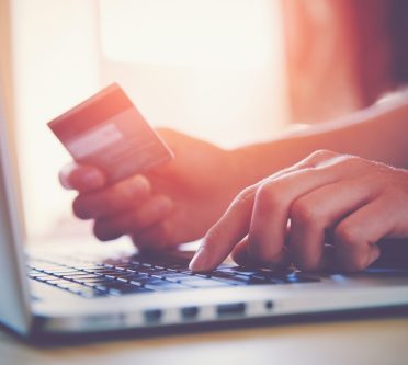 Person bezahlt eine Rechnung am Computer mit Kreditkarte