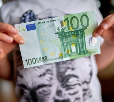 Das Foto zeigt einen jungen Menschen, der einen 100 Euro-Schein in die Kamera hält. Neuer Tarifvertrag sorgt für mehr Geld bei den Azubis in NRW