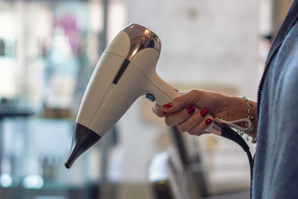 Airtouch: Die ultimative Haartechnik für einzigartig, natürliche Strähnen 2025 1 Eine Hand hält einen weißen Föhn.
