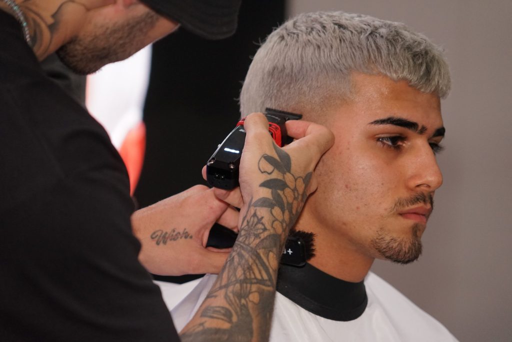 Haartrends: Diese Frisuren müssen Männer im Herbst 2025 kennen 1 Ein Barber schneidet mit einer Haarschneidemaschine einen French Crop Fade Cut.