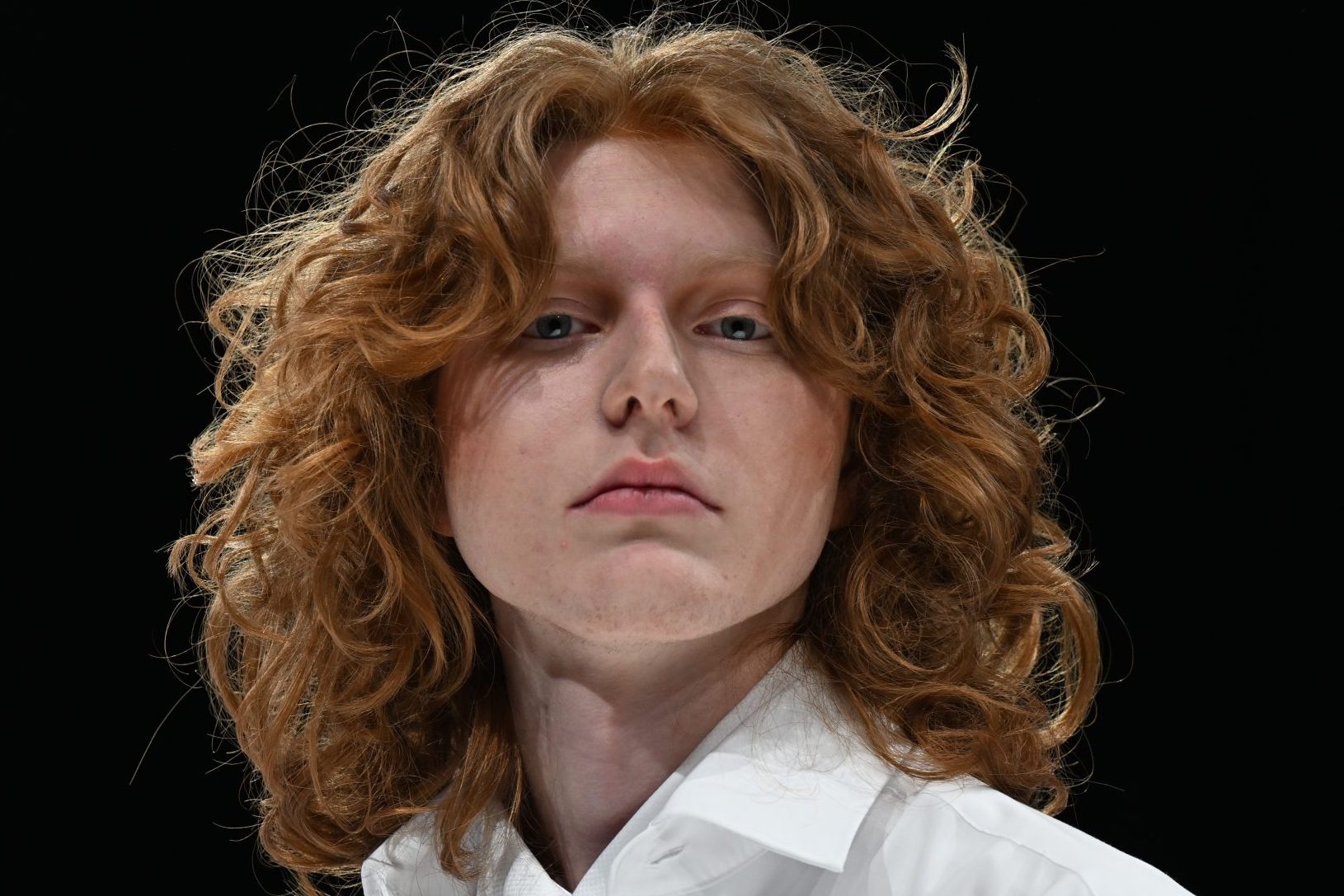Retro-Frisuren für Männer erleben 2025 ein Revival 6 Frontalansicht eines rothaarigen Mannes. Er trägt gestufte lange Locken und Curtain Bang