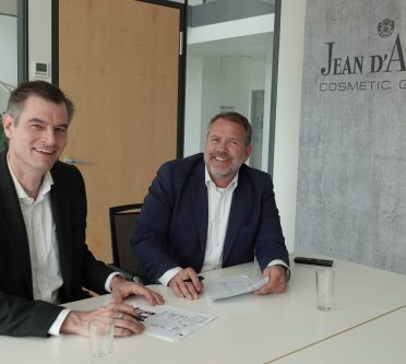 An einem Tisch sitzt Dr. Peter Steck, der von Daniel Sergent den Posten des Geschäftsführers (v.l.) der Jean D'Arcel Group übernimmt.