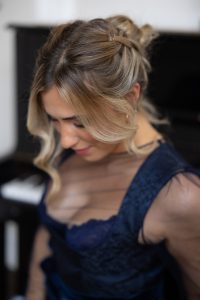 Das Bild zeigt eine Frau im blauen Dirndl, mit einer Duttfrisur.