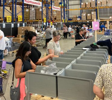 Frauen schauen Artikel in einem Logistiklager an, kaufen ein, Messeverkauf
