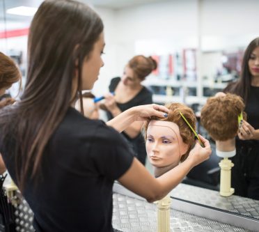 Junge Frau frisiert Puppenkopf