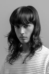 Bild einer längeren Männerfrisur, wellig, mit Pony, leichte Wet-Optik