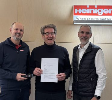 Drei Männer schauen ins Bild, einer hält die Urkunde zur Partnerschaft in Händen, Partnerschaft Zentralverband Frseurhandwerk & Schneide-Equipement Hersteller Heiniger_