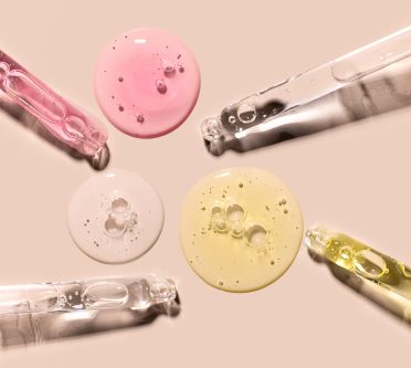 Zu sehen ist ein Close-up von vier Pipetten und drei farbigen Seren