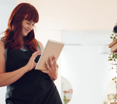 Frau lehnt an der Wand mit Tablet in der Hand