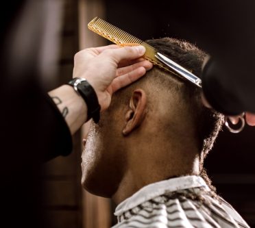 Eine Herrenfrisur wird Schere über Kamm geschnitten