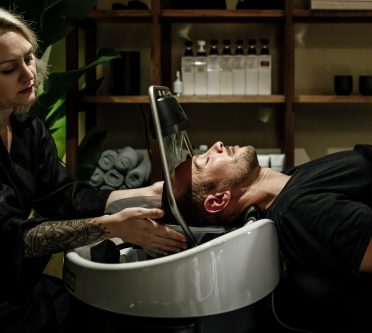 Frau führt eine Head Spa-Behandlung durch, Wasserfallanwendung, Mann liegt auf Liege