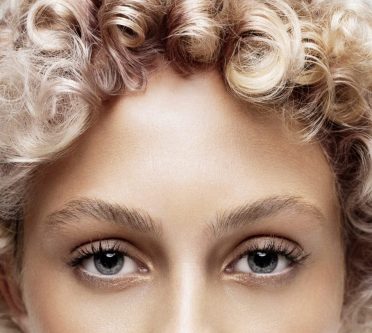 Model mit kurzer, blonder Lockenfrisur