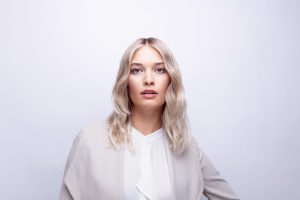 Beyond Blonde - der F/S-Trend vom ZV Friseurhandwerk 7 Bild einer Frau mit platinblondem, schulterlangem, leicht gewelltem Haar.