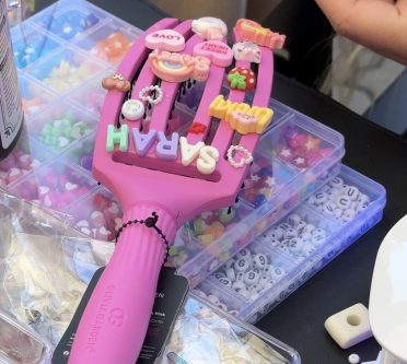 Eine pinke Haarbürste mit bunten Buchstaben und Motiven zum Draufkleben