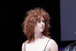 Workshop-Trend Stufen 5 Frau mit kupferbraunem, lockigen, stufig geschnittenen Haar auf einem Laufsteg