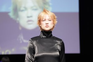 Workshop Stage 2026 33 Frau mit blondem, kurzem Haar auf einem Laufsteg