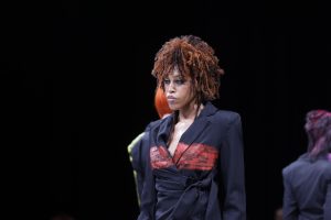 Workshop Stage 2026 19 Eine Frau mit Coily Hair in Kupfer- und Brauntönen auf einer Bühne