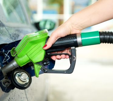 Hand hält Tankstutzen in den Tank eines PKWs