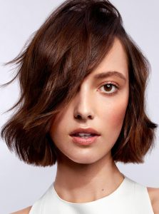 Trend-Kollektion Label.M 2 Eine Frau mit einem welligen, kinnlangen Bob in warmen Brauntönen, leicht seitlich gestylt