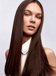Trend-Kollektion Label.M 10 Eine Frau mit langem, braunen Haar, das super glatt gestylt vom Mittelscheitel aus über die Schultern fällt