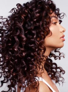 Trend-Kollektion Label.M 4 Eine Frau mit langem Haar, das in glänzenden, dunkelbraunen Locken über die Schultern fällt