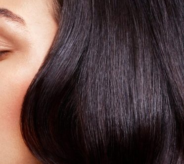 Eine Frau mit langem Haar, das in glänzenden, dunkelbraunen Wellen über die Schultern fällt