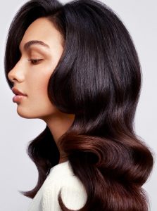 Trend-Kollektion Label.M 3 Eine Frau mit langem Haar, das in glänzenden, dunkelbraunen Wellen über die Schultern fällt