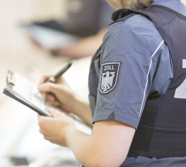 Arm einer Zöllnerin als Symbolbild für den Zoll mit Wappen des Zoll