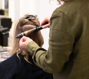 Foto zeigt Friseurin, die Kundin mit Lockenstab stylt. Foto : Melanie Fredel