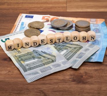 Geldscheine und Münzen. Darauf liegen Würfen, die das Wort 