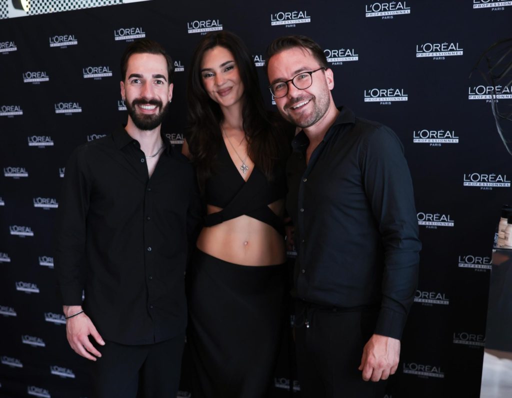 Premiere bei L’Oréal Professionnel: Stefanie Giesinger wird Markenbotschafterin 5 Niko Papadopoulos und Raphael Murg von L‘Oréal Professionnel stehen mit Stefanie Giesinger vor einer schwarzen Wand mit weißen Logos