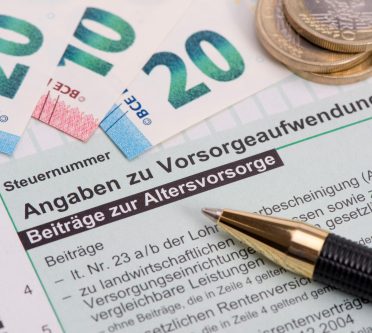 Formular Altersvorsorge, darauf liegt Geld und ein Kugelschreiber