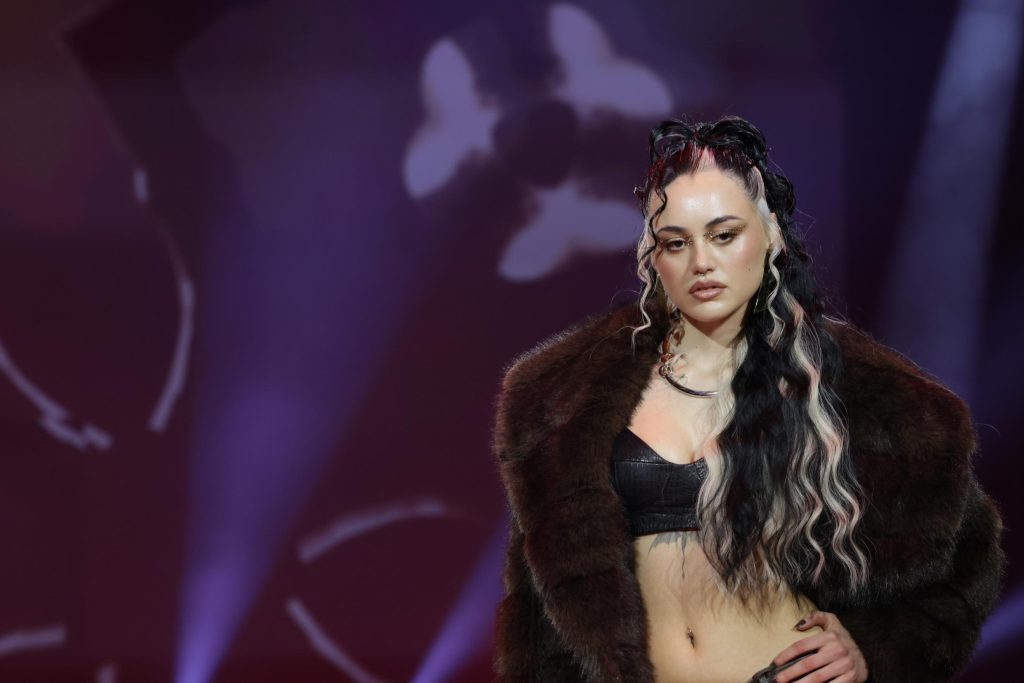 Das Bild zeigt eine Frau mit langen Haaren im Half Bun Style. Die schwarzen Haare sind mit markanten hellblonden Strähnen unterbrochen