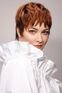 Trend Intercoiffure Austria 4 Pixie Cut mit fransig in die Stirn gestyltem Pony, in intensivem Kupferrot mit dunkleren Ansätzen
