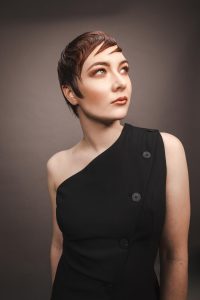 Trend Intercoiffure Austria 9 Kurzer, dunkler Pixie Cut mit glatter Textur und im Wet Look gestyltem, seitlich über die Stirn gelegtem Pony.