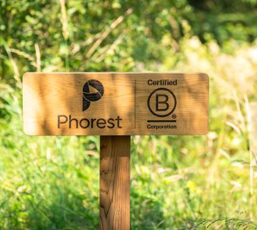 Holzschild mit dem Firmennamen Phorest und dem Logo der B Corp Zerifitzierung