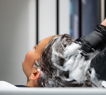 Frau bekommt beim Friseur Haare gewaschen