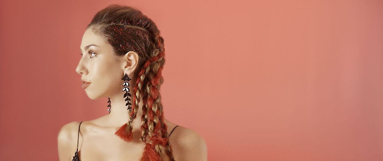 junge Frau mit langen, geflochtenen haare, roten Kunsthaarelementen und glitzerndem Wet-Hair-Effekt